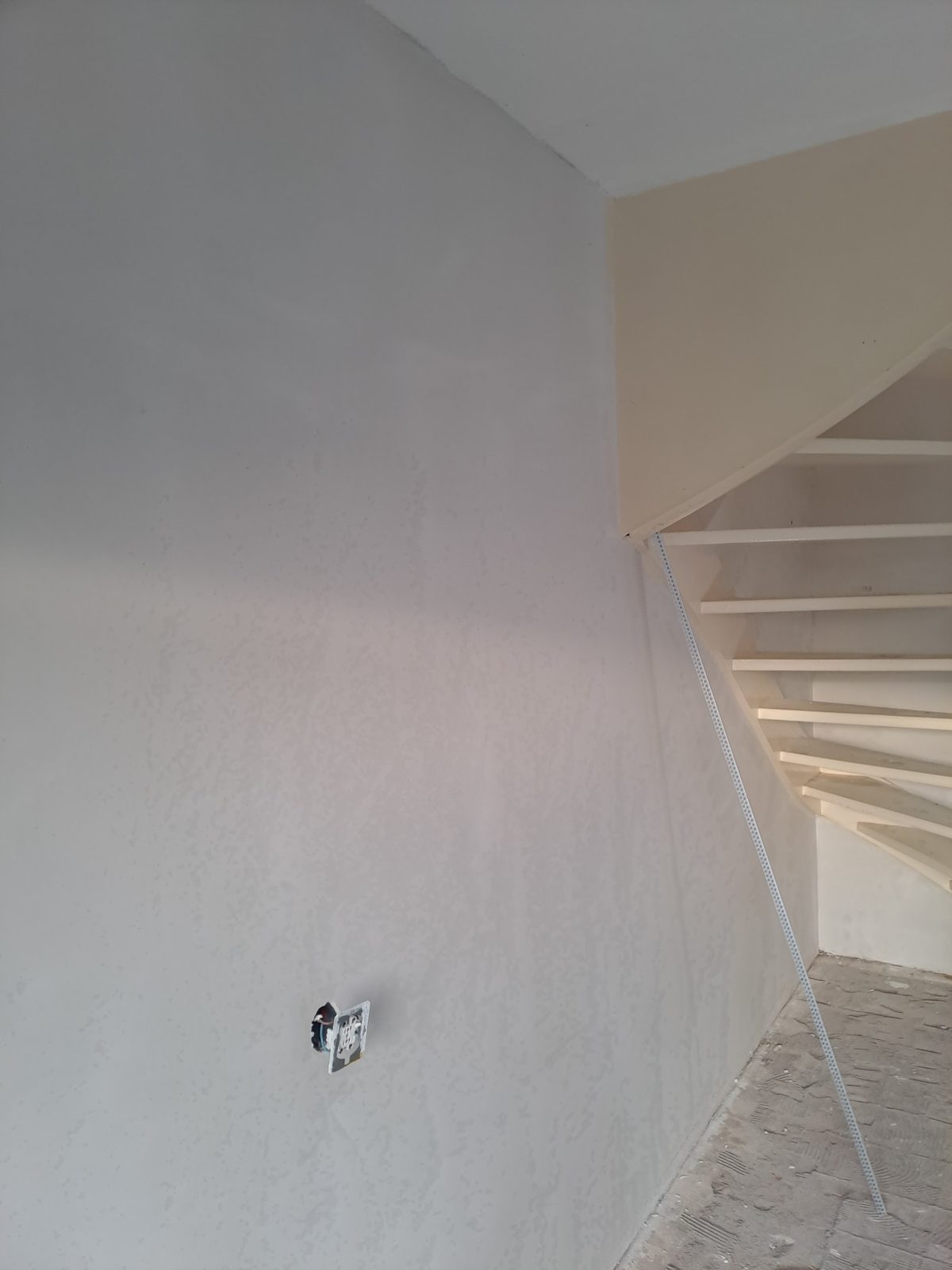 Glad gestucte wand naast een trap in een huurwoning