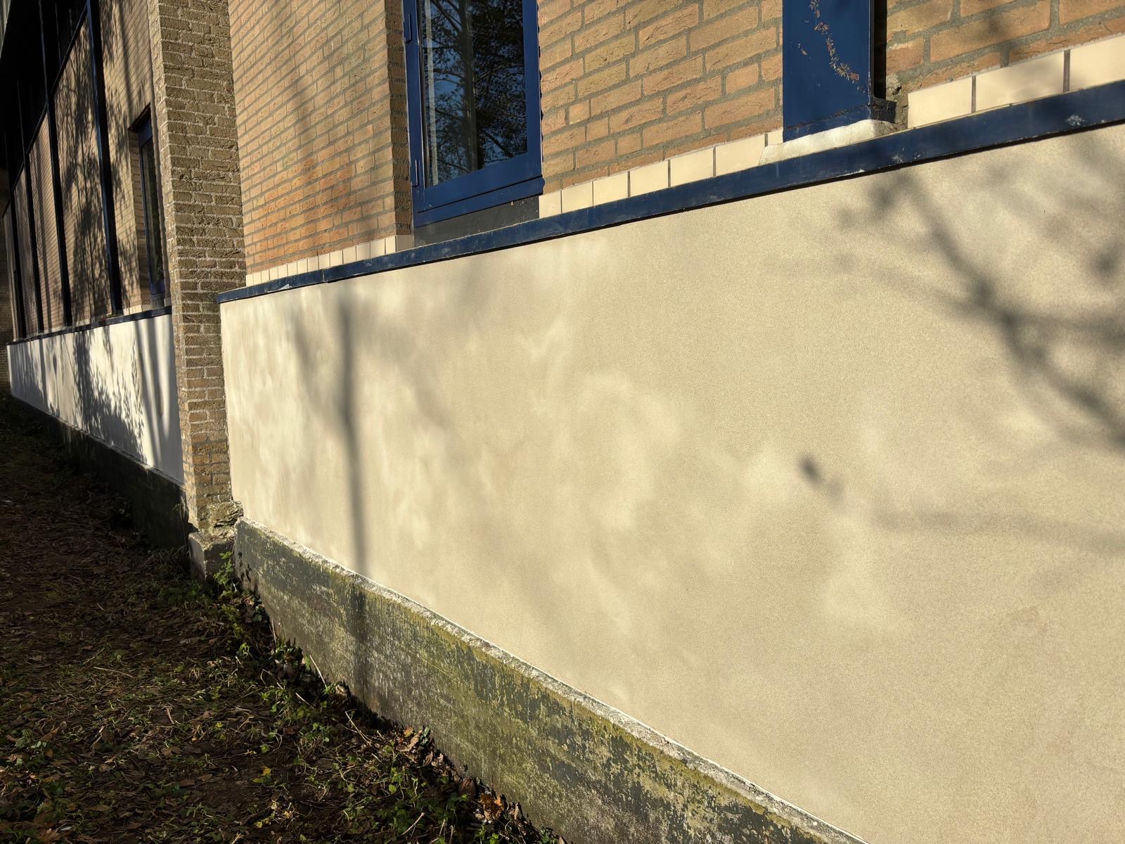 Nieuw gestucte gevelplint in een lichte kleur onder het metselwerk, aan de tuinkant